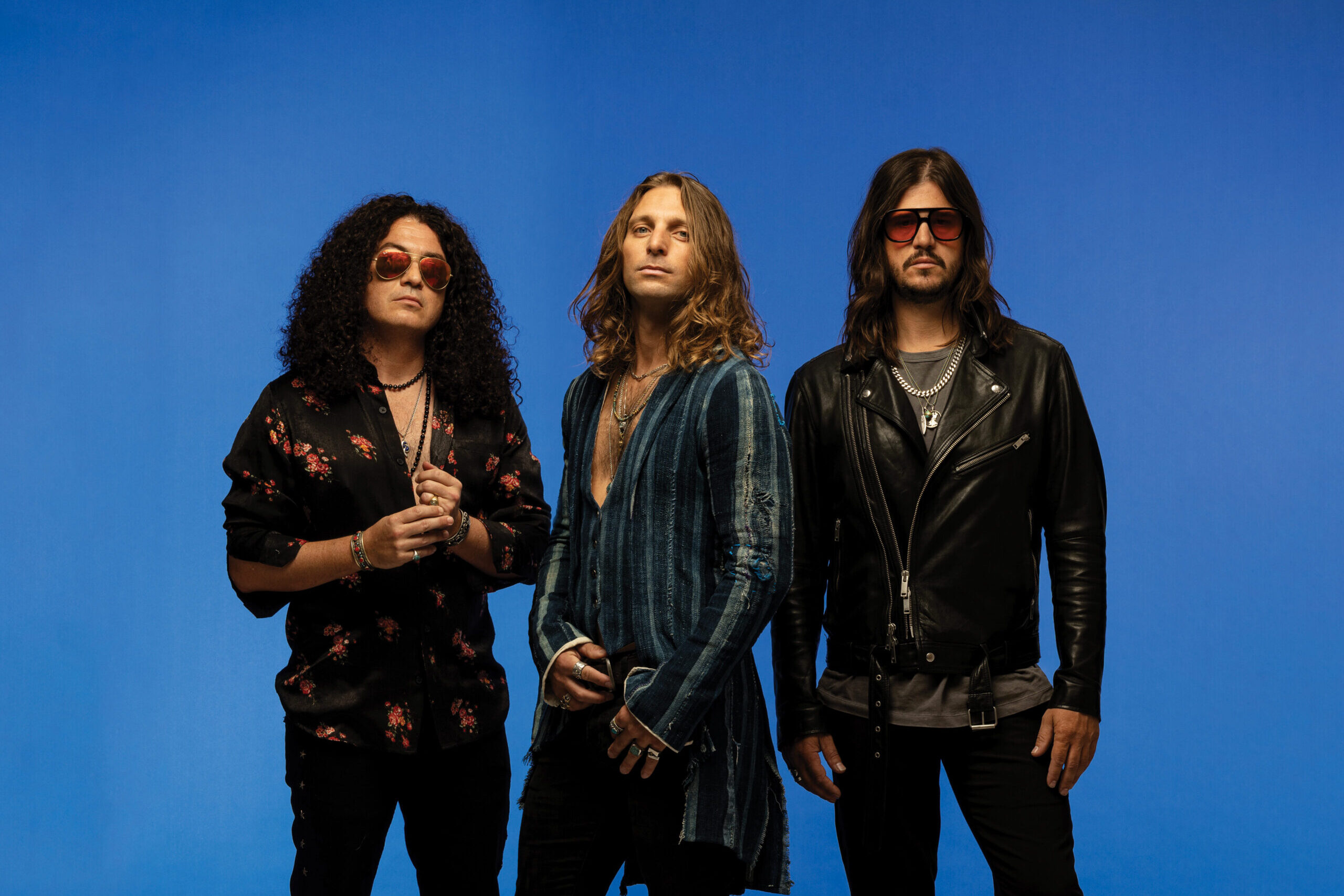 Dirty Honey band members stand in front of a blue background